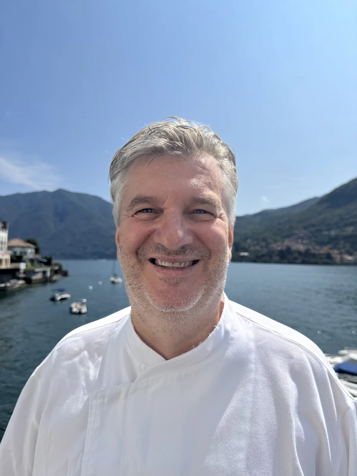 Lo Chef Alessio Rossi sorride davanti al Lago di Como
